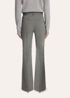 A model stands against a light studio background wearing a tailored light gray pinstripe suit with a white shirt, patterned tie, and black pointed shoes.