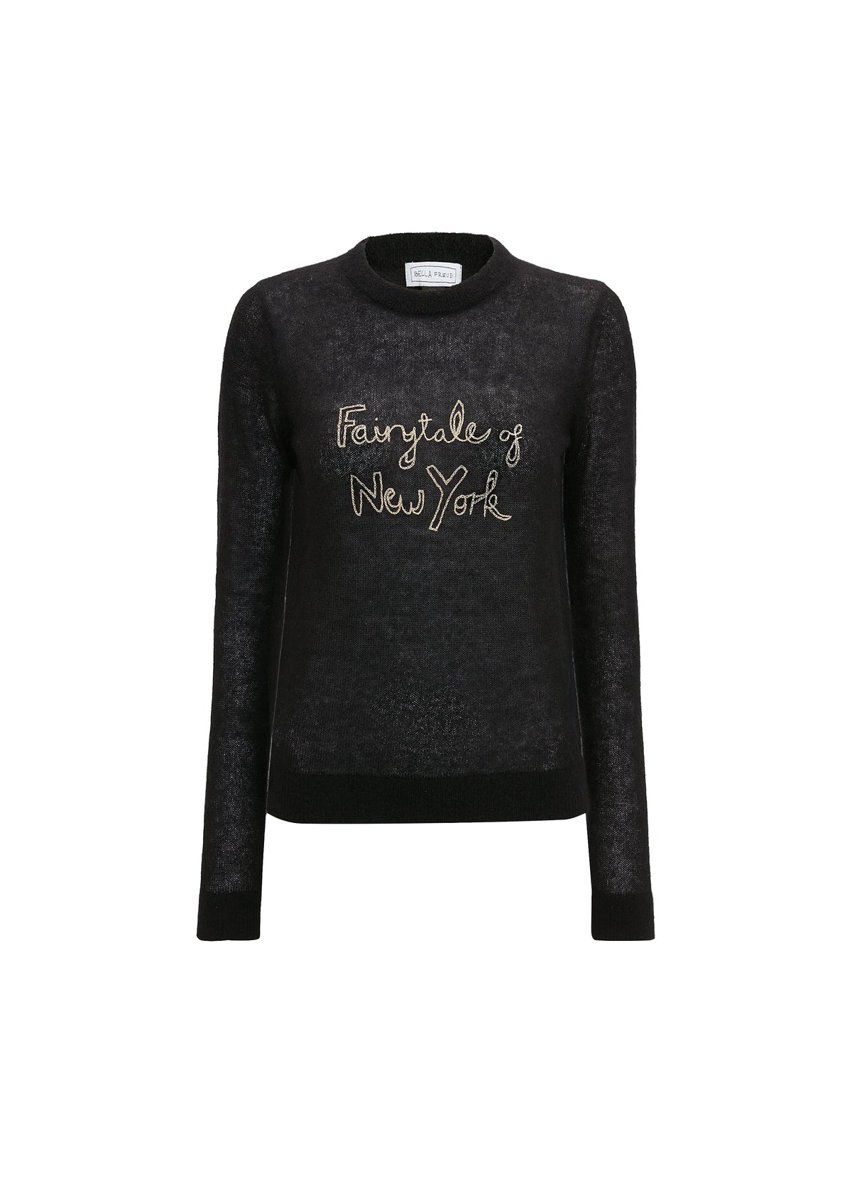 A model wearing a black long-sleeve knit sweater with a light pink collar and 'Fairytale of New York' embroidered in gold on the chest, styled with a light pink collared shirt and cream trousers against a light gray background.